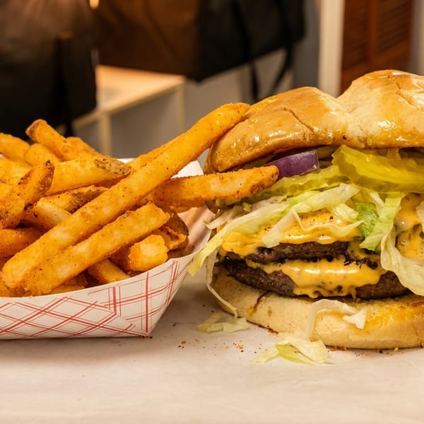 A double cheeseburger with lettuce, onions, pickles, and special sauce, served with a side of seasoned fries.