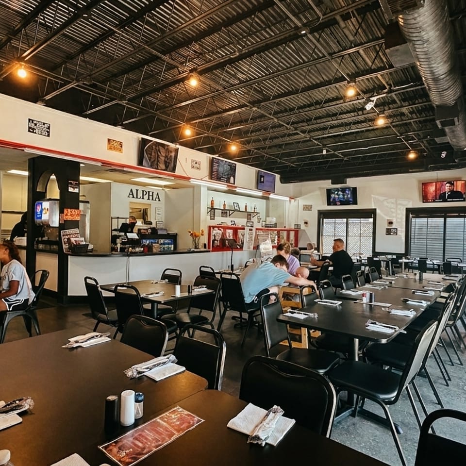 Spacious, casual dining room with black tables, chairs, and a counter, with patrons seated.